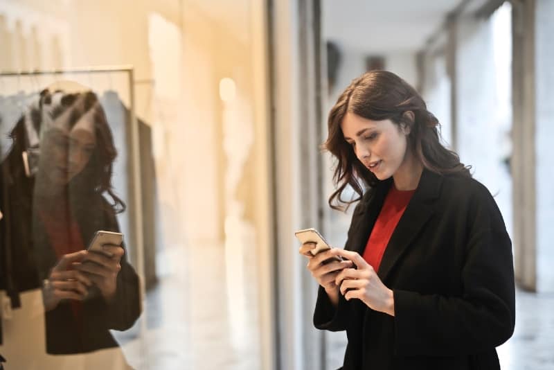 donna con cappotto nero che usa lo smartphone
