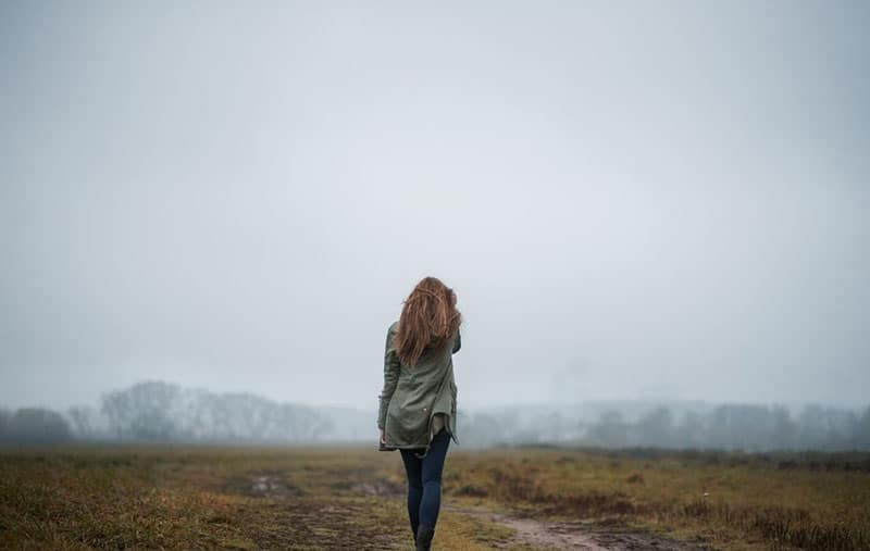 woman walking towards the foggy mountain