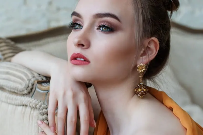 woman wears make up and big earrings dressed elegantly