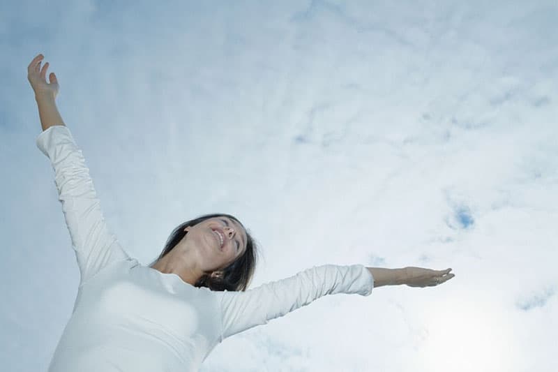 woman with arms raised wearing white long sleeves in low angle 