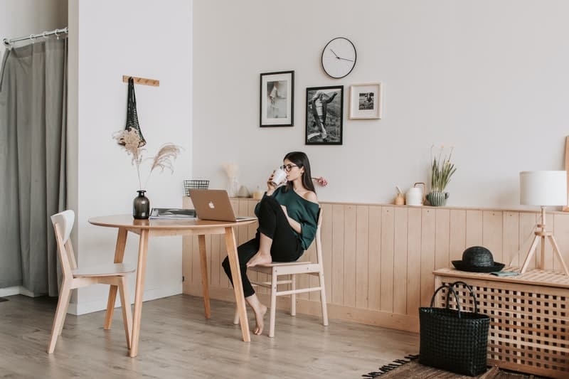 donna che lavora a casa e beve caffè seduta in modo rilassato alla sua sedia