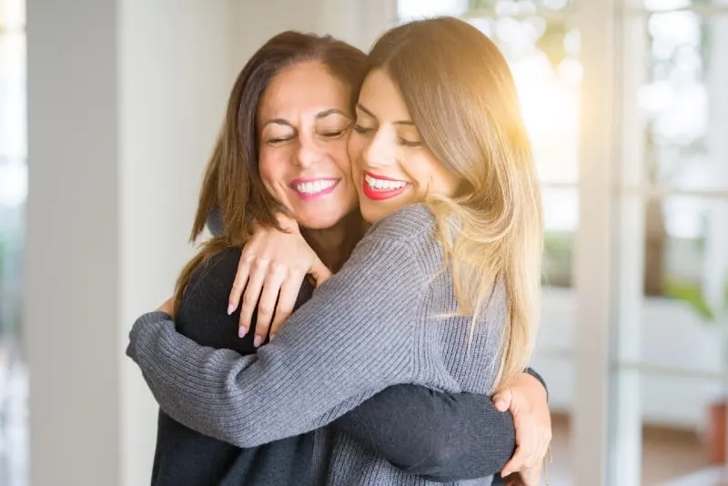 two women hugging while standing indoor