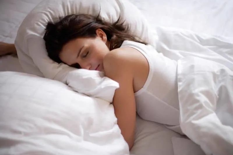 young woman sleeping soundly in white linen bed