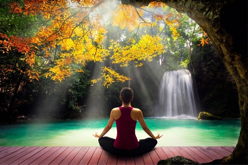 young woman posing yoga near a beautiful nature and waterfalls