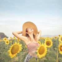smiling woman with hat standing on sunflowers field
