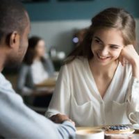 interracial man and woman flirting while having coffee inside a cafe