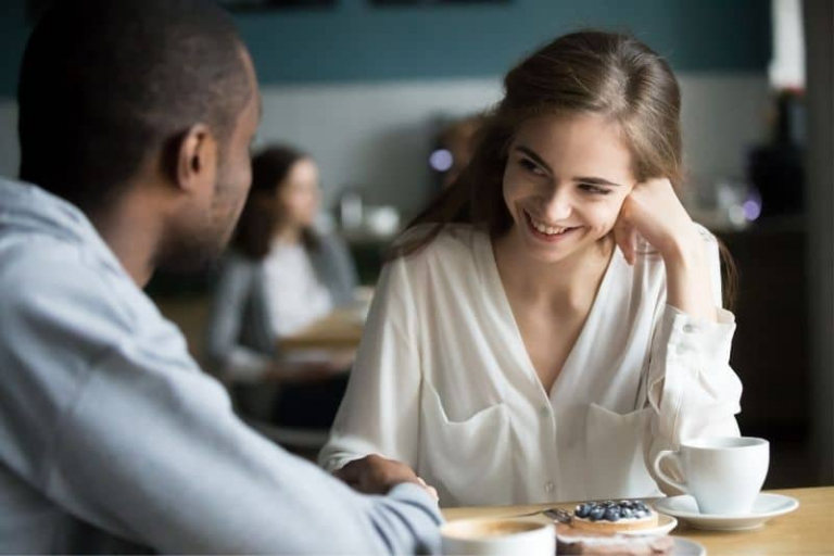 interracial man and woman flirting while having coffee inside a cafe