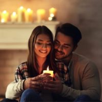 joven pareja feliz quemando una vela en casa