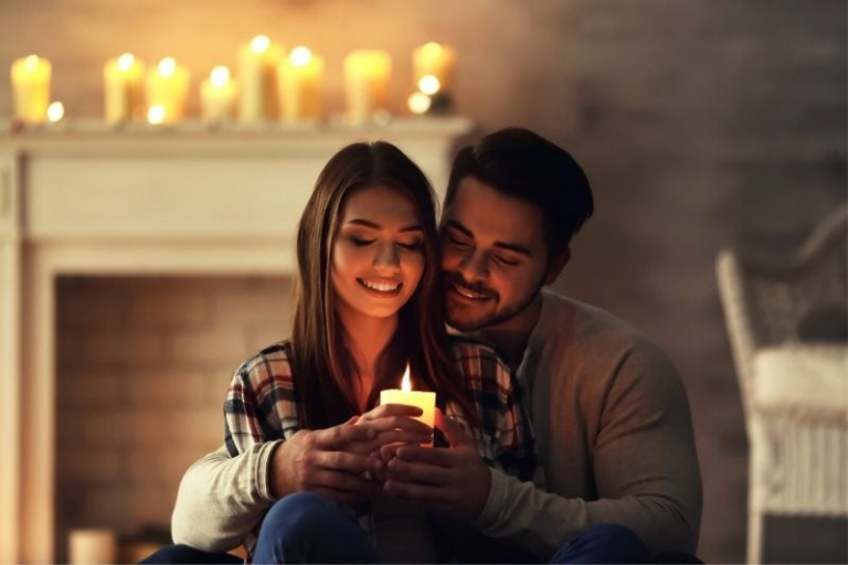 happy young couple burning candle at home