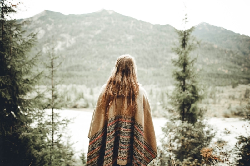 woman in brown poncho looking at mountain