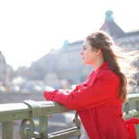 woman in red coat standing on bridge