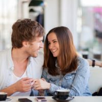 cheerful couple talking inside a cafe with their coffee