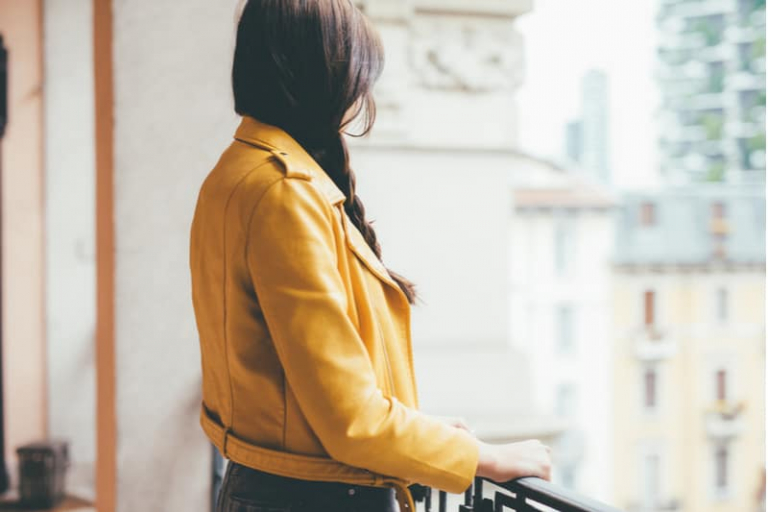 back view of a caucasian woman looking outside thru the veranda