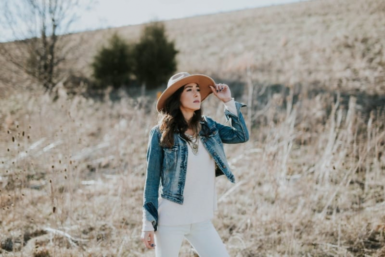 woman holding hat while standing in the field