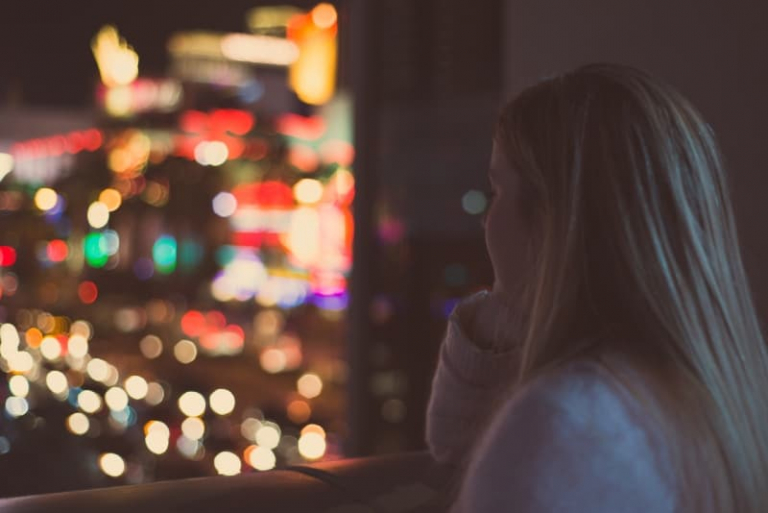 blonde woman looking outside window at night