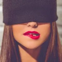 stylish young woman with black cap on hiding her eyes biting her lip