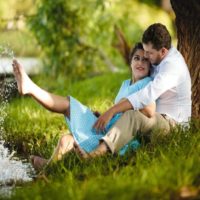 uomo e donna seduti sull'erba sotto l'albero