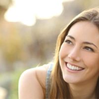 mujer con dientes blancos sonriendo pensando y mirando a su extrema derecha