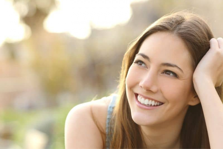 woman with white teeth smiling thinking and looking on her far right
