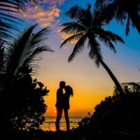 man kissing woman's forehead near sea