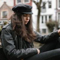 mulher com casaco de cabedal preto sentada junto ao canal da cidade