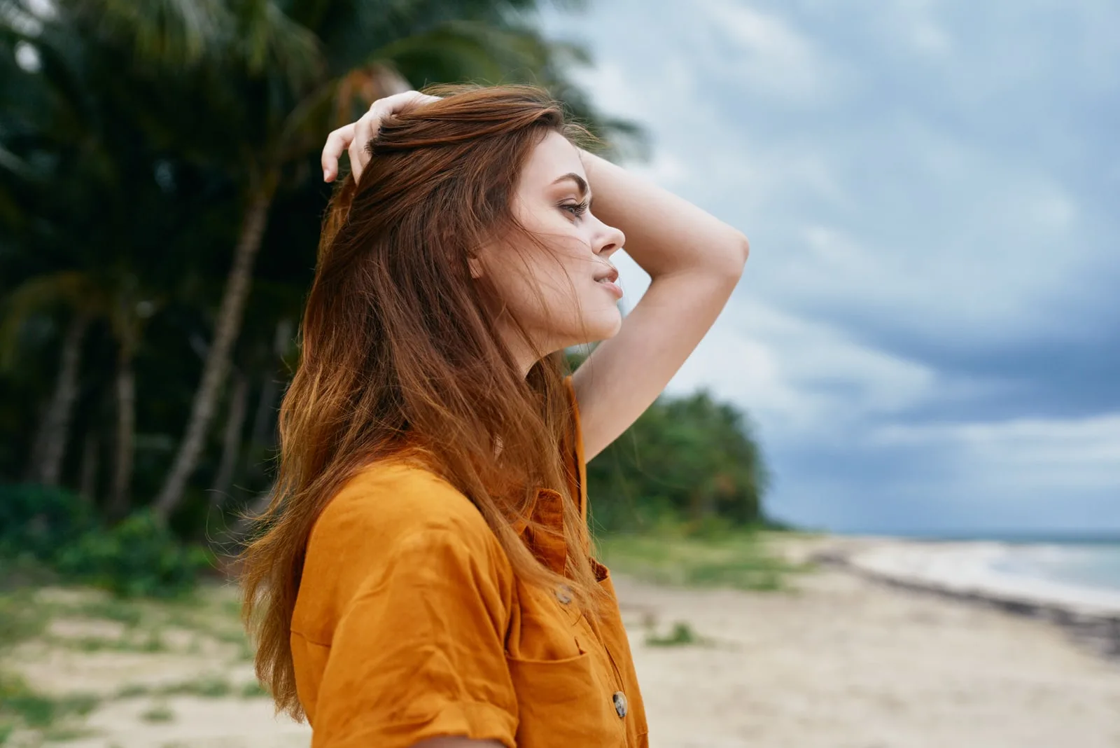 a beautiful red-haired girl in a yellow T-shirt stands on the beach