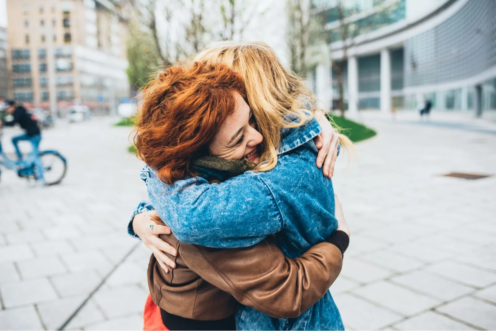 a blonde and redhead girl hugging in the street