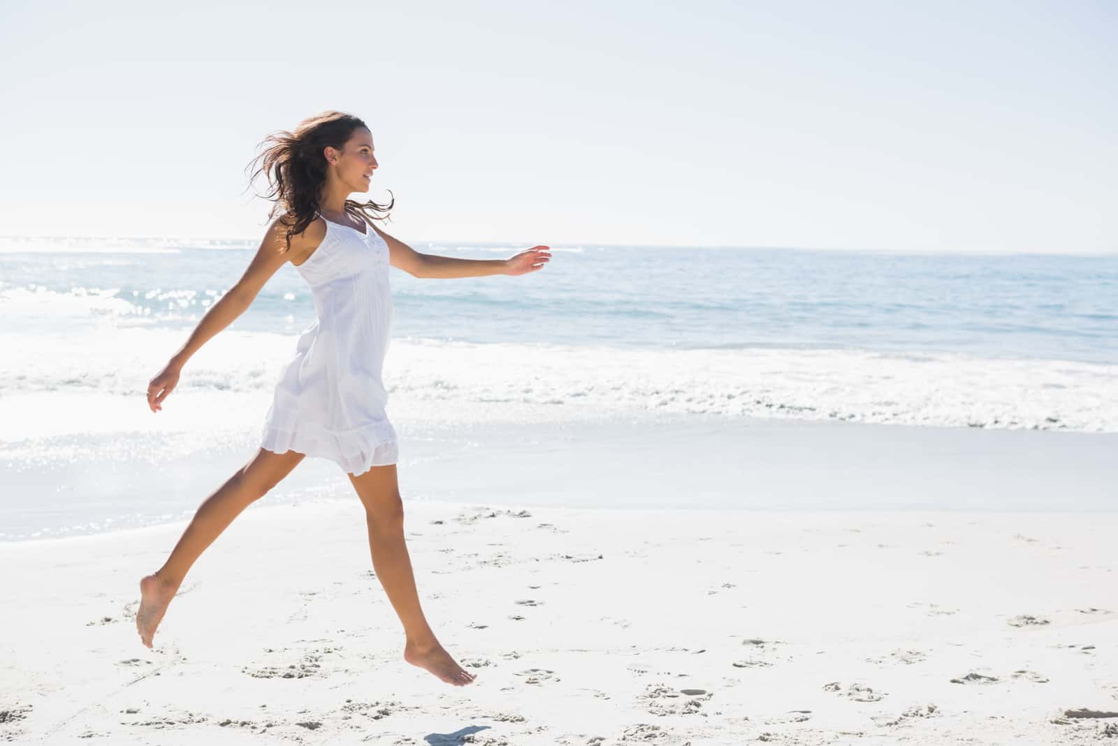 a woman with long brown hair runs across the beach