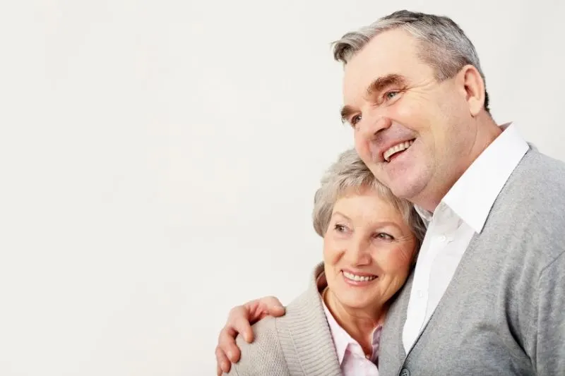 adult couple hugging wearing same shade of gray top standing against white background