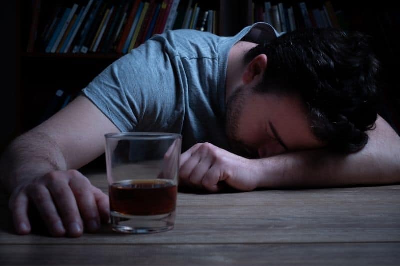 un uomo dipendente dall'alcol si è addormentato mentre beveva birra nel bicchiere