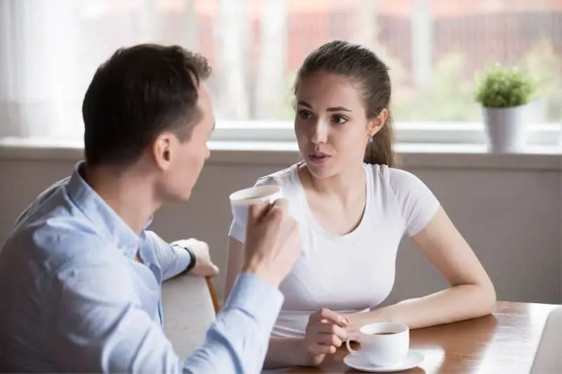 attractive young serious couple talking over coffee indoors