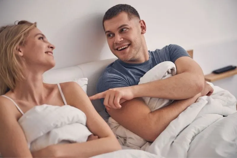 beautiful couple laughing while lying in bed