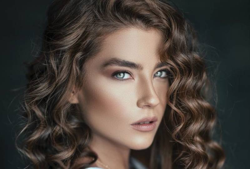 beautiful curly haired woman with make up on face in focus