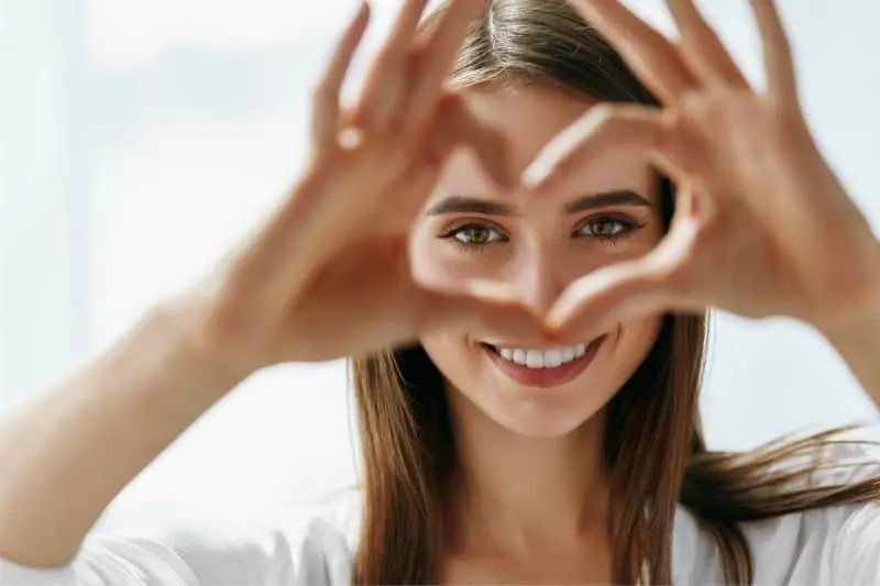 beautiful happy woman showing love signs near her eyes