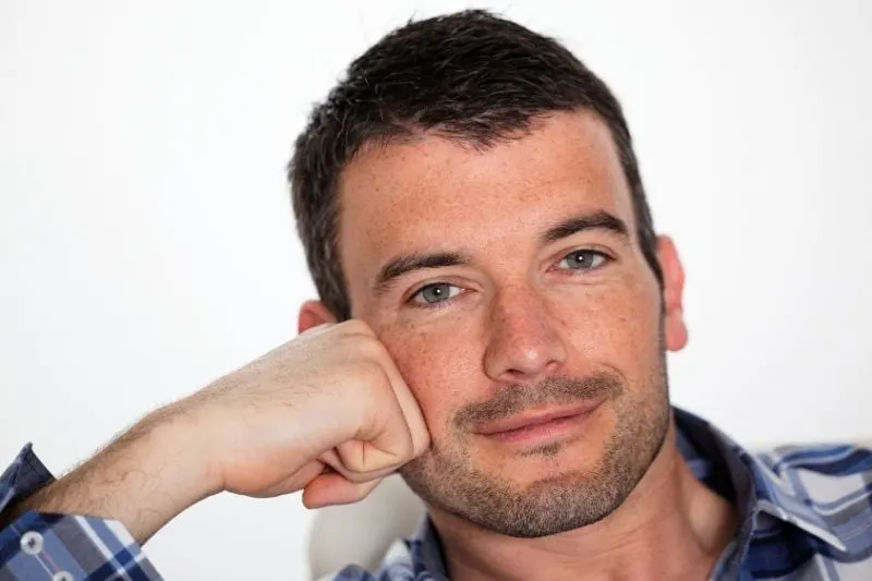 beautiful pensive man leaning on his fist in white background