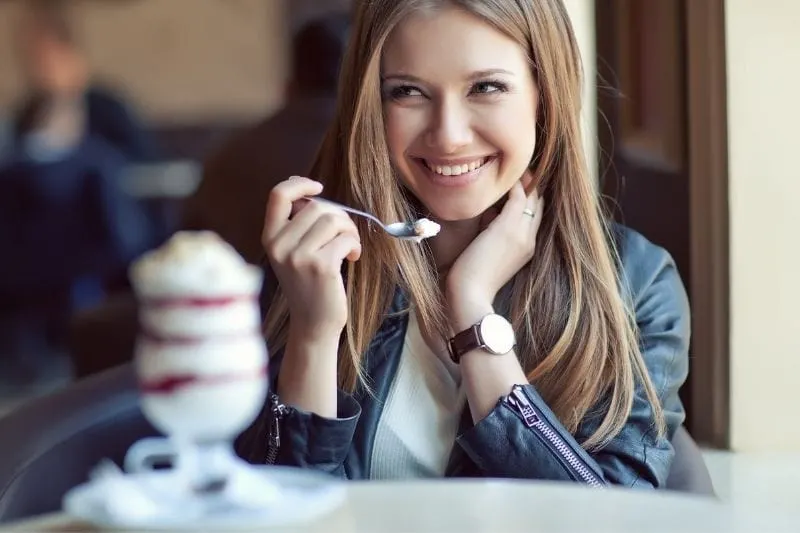 beautiful woman eating dessert smiling while looking and giggling