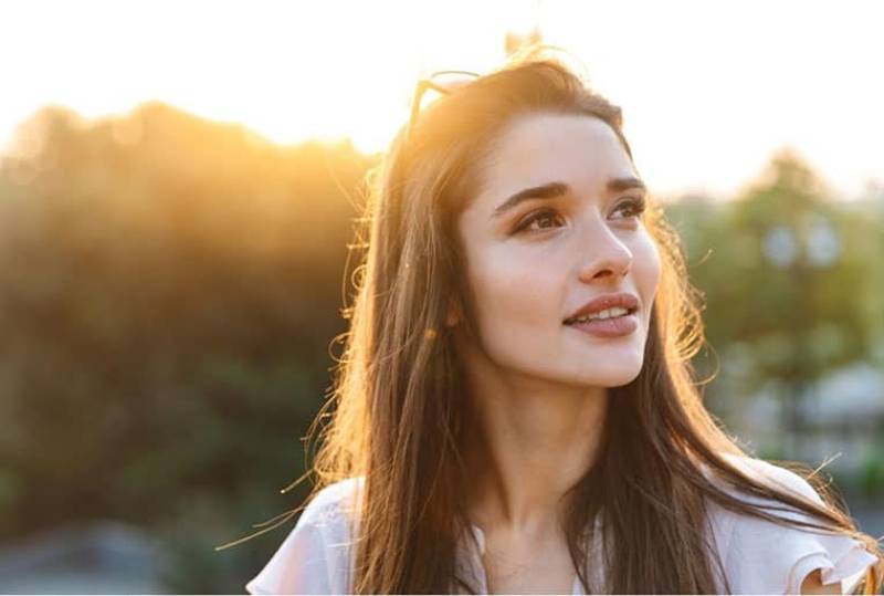 beautiful woman smiling outdoors during sunrise looking forward to a beautiful day