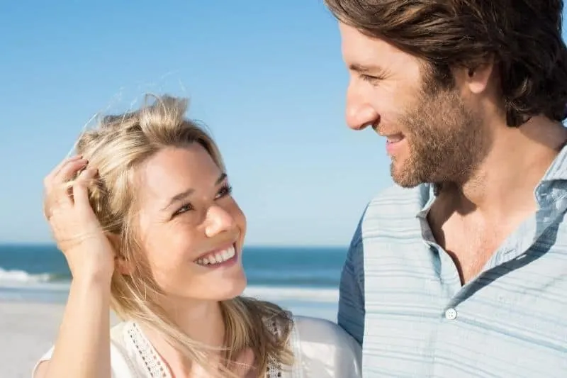 cheerful man looking at a woman smiling near the body of water
