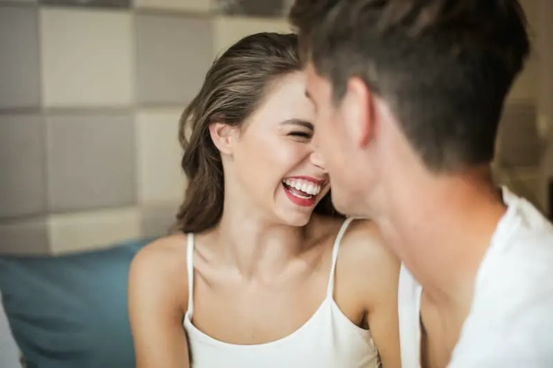 cheerful young couple laughing inside the bedroom wearing white top
