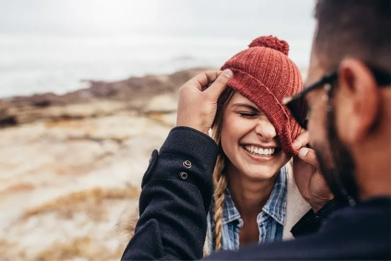 close photo of a couple laughing putting the bonnet on the woman incorrectly outdoors