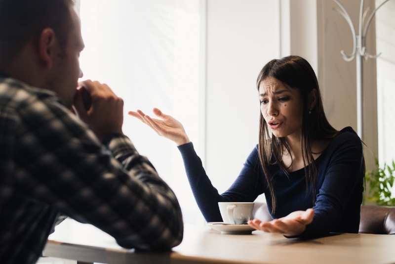 man and woman arguing while sitting at table in cafe