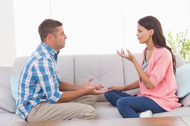 man and woman arguing while sitting on sofa