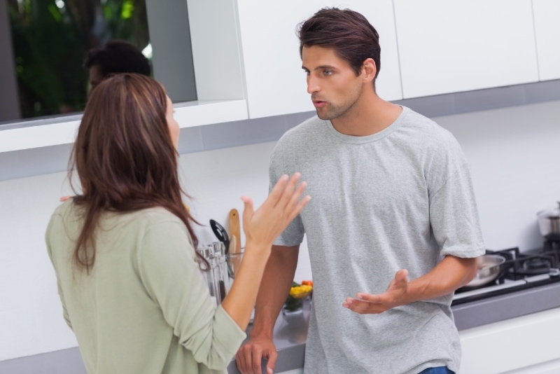 man and woman arguing while standing in the kitchen