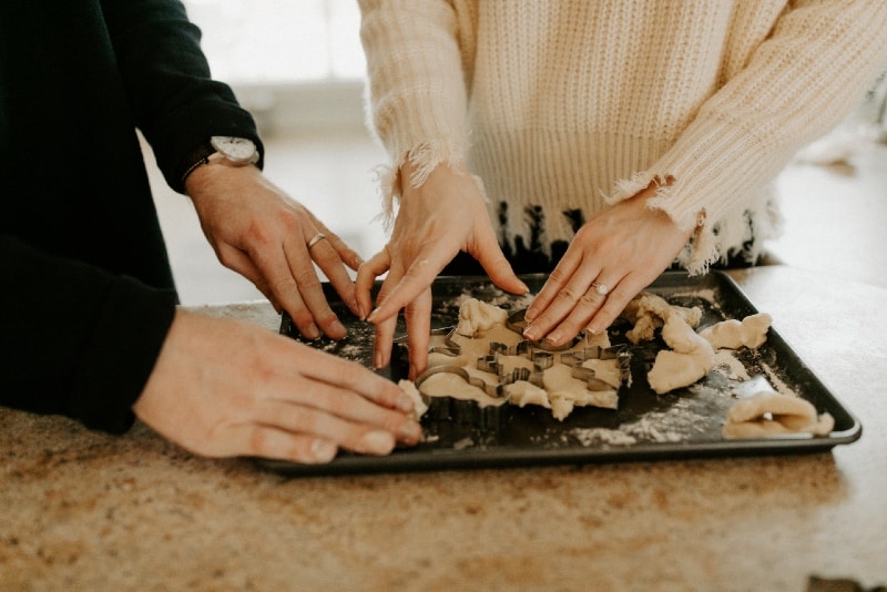 woman in white sweater and man baking cookies