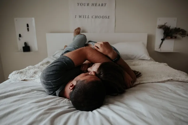 man and woman cuddling while lying on bed