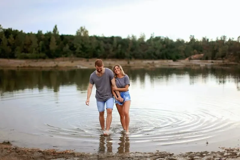 couple enjoying the lake together holding hands wearing denim shorts 