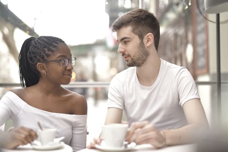 uomo e donna che si guardano negli occhi mentre prendono un caffè