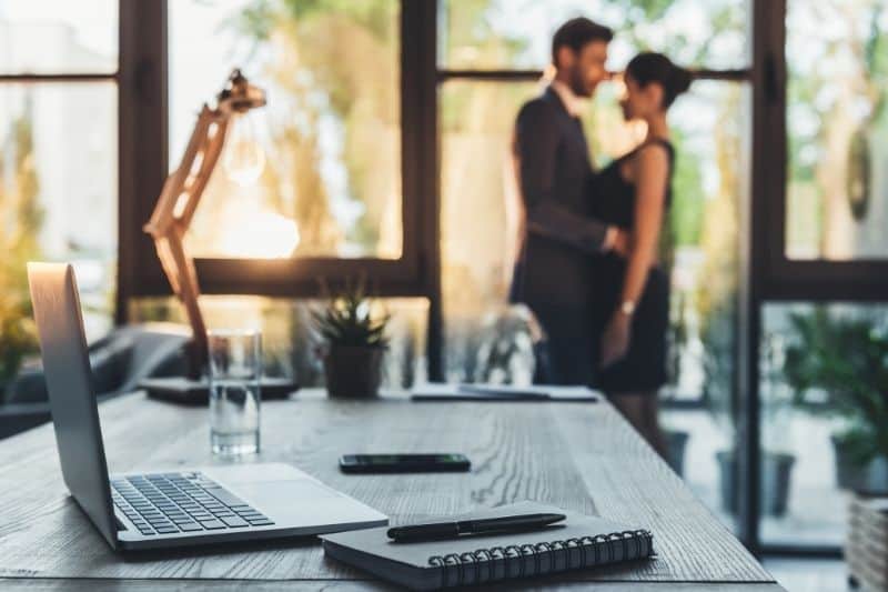 casal no escritório a abraçar-se no fundo desfocado da mesa do escritório 