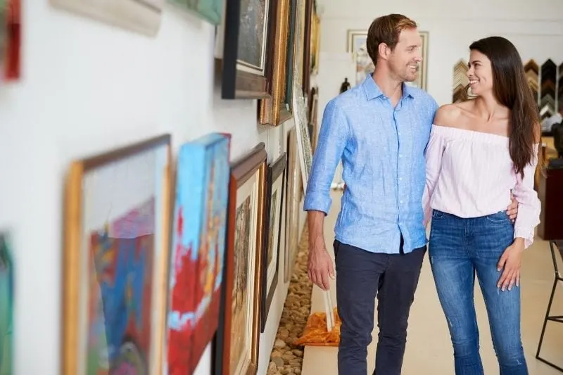 couple inside an art gallery with man's arms around the woman's waist