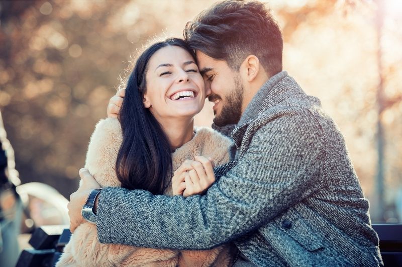 pareja riendo al aire libre hombre abrazando a la mujer